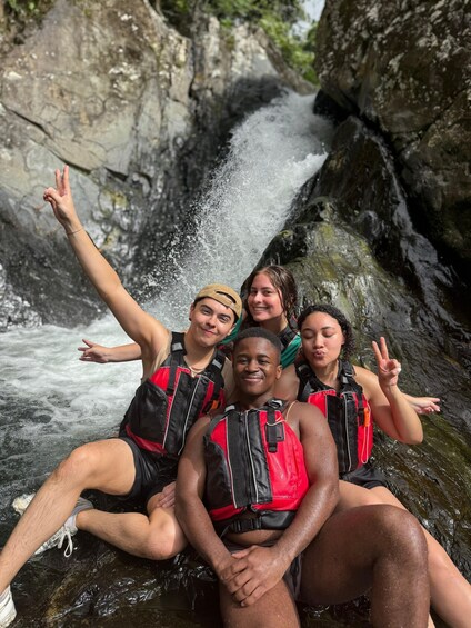 A group of people sitting on rocks by a waterfall. 5