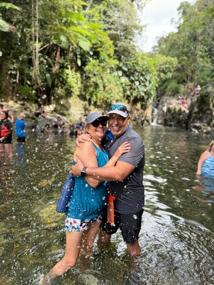 A couple embracing in a natural water setting surrounded by greenery. 3