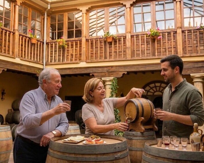 A man pouring wine from a barrel, a woman holding a glass, and another man observing. 1