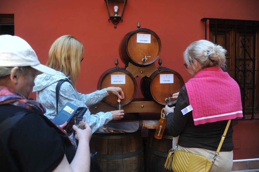 Four wooden barrels with labels, a red wall, and a window. 4