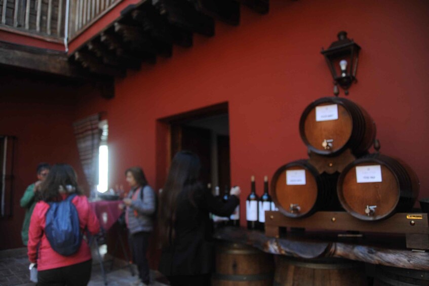 A red building with wooden barrels stacked outside, a person with a backpack, and a street lamp. 5