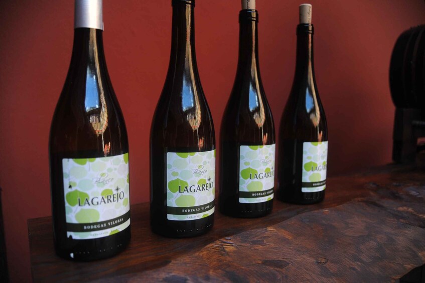 Three bottles of Lagarejo wine on a wooden surface against a red background. 3