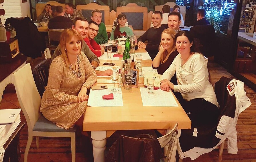 A group of people seated at a wooden table in a restaurant with a menu and glasses of water. 2
