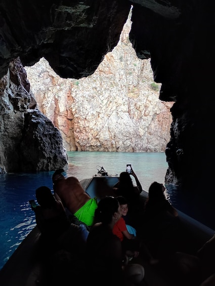 A boat tour through a cave with rocky walls and clear water. 2