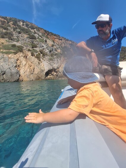 A boat on clear water with rocky cliffs in the background. 5