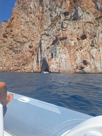 A rocky coastline with a small boat near a cave entrance. 3