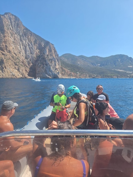 A group of people on a boat near a rocky coastline. 4