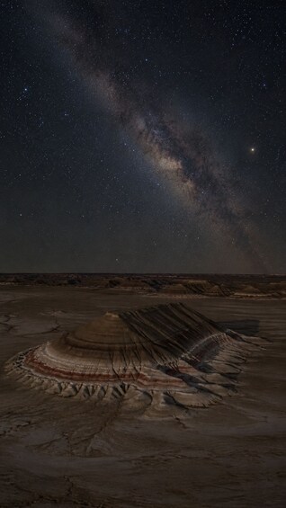 A starry night sky over a geological formation with layered rock patterns. 4