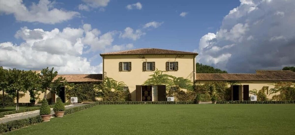 A two-story building with a tiled roof, surrounded by a well-maintained lawn and garden. 5