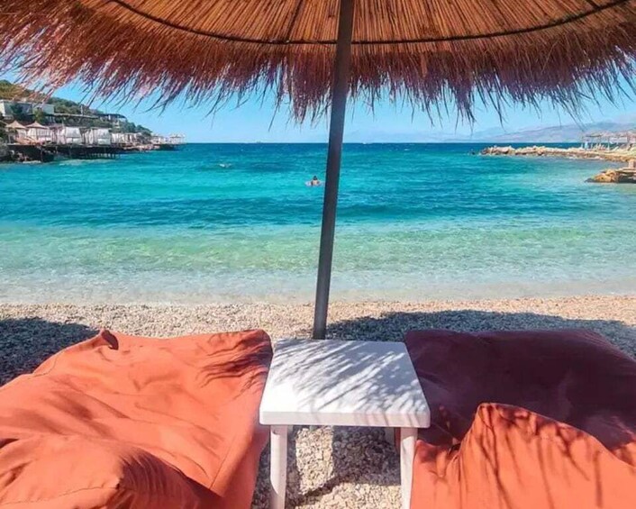A beach with clear turquoise water, a thatched umbrella, and a table. 3