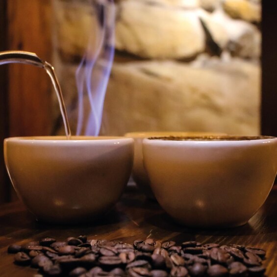 Two ceramic cups with a steaming beverage, surrounded by scattered coffee beans on a wooden surface. 4