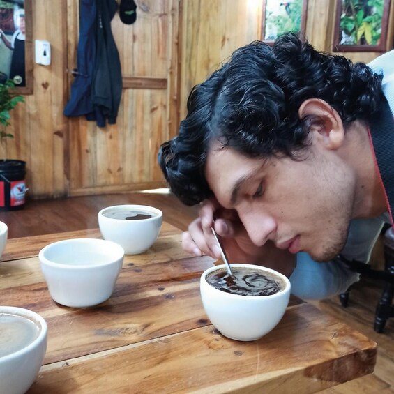 A person sitting at a wooden table with several white bowls, one containing a dark liquid, likely coffee. 5