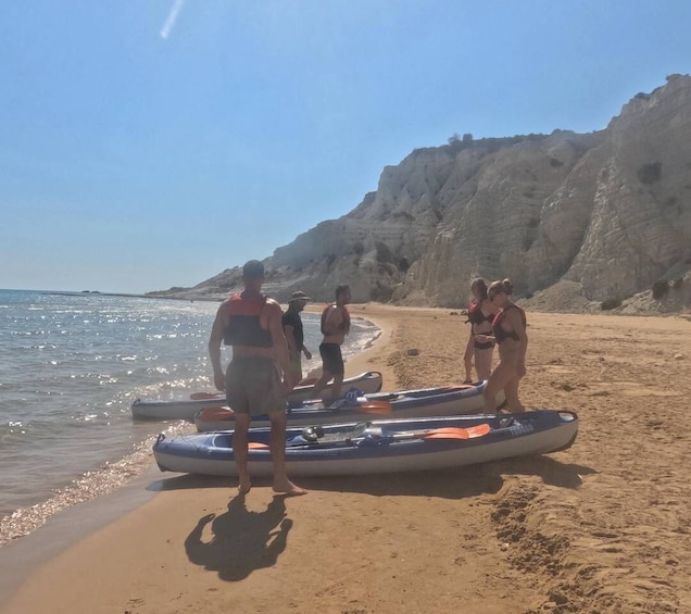 A beach with people preparing kayaks. 5