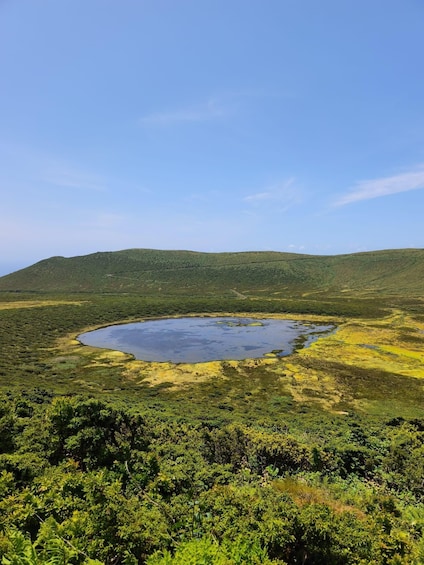 A lake surrounded by green hills and dense vegetation. 5