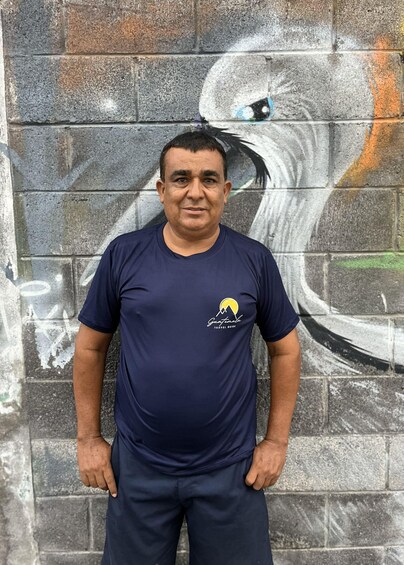 A man standing in front of a mural on a brick wall. 2