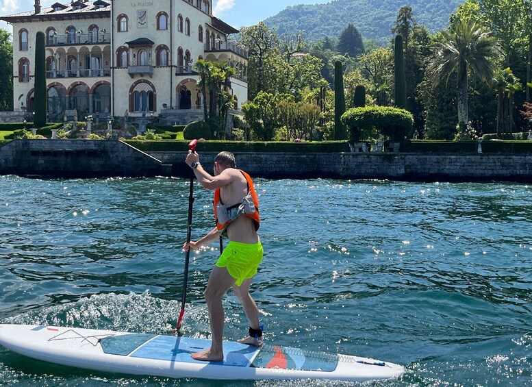 A person paddleboarding on a calm body of water with a historic building in the background. 4