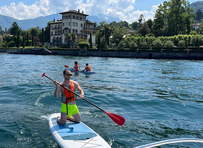 A person paddleboarding on a calm lake with a historic building in the background. 2
