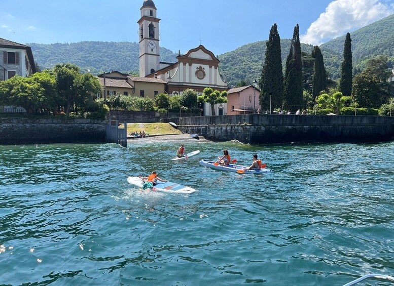 People kayaking on a calm lake with a church and mountains in the background. 5