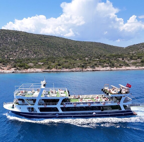A ferry named Poseidon traveling on a body of water with a mountainous landscape in the background. 3