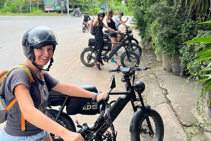 A person on a black electric bike with a backpack, another on a motorcycle, and a third on a bicycle. 5