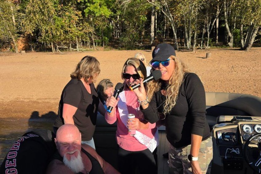 Un grupo de personas en un bote, una playa de arena y árboles al fondo. 4