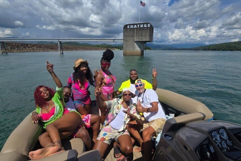 A group of people on a boat near a bridge with the word 'CHATUGE' on it. 2