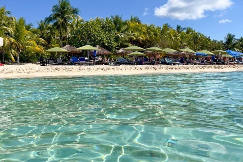 A beach with clear turquoise water, palm trees, and beach umbrellas. 4