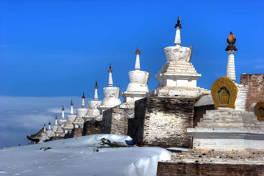 Una fila de estupas cubiertas de nieve con diseños intrincados y un cielo azul despejado. 2