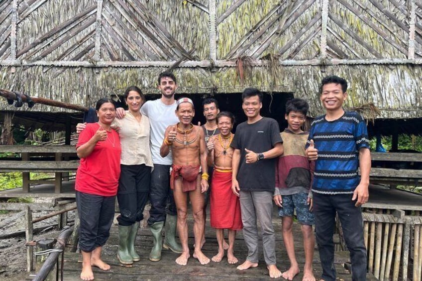 A group of people standing in front of a thatched-roof structure. 4