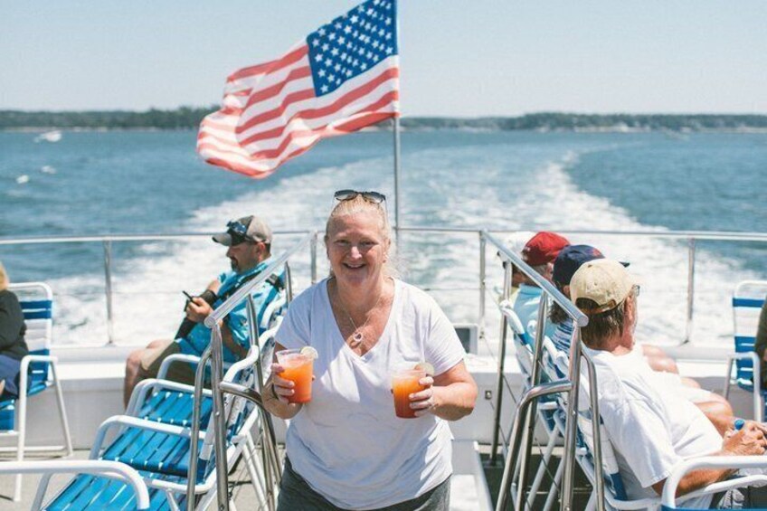 A boat with people on board, an American flag, and a body of water in the background. 4