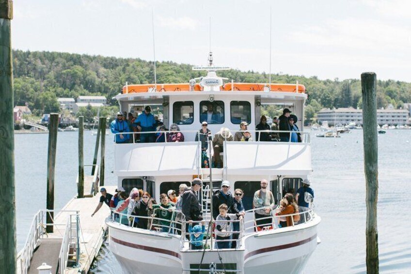 A boat docked at a pier with people on board. 2