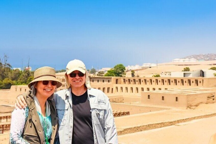 Two people standing in front of a desert landscape with traditional buildings. 2
