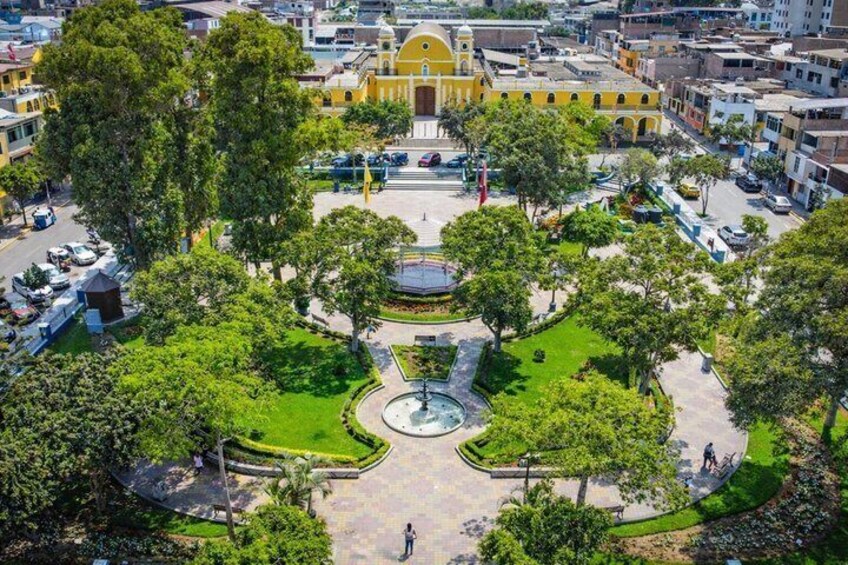 A park with a fountain, surrounded by trees and buildings. 1