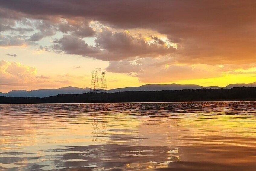 A sunset over a calm lake with power lines in the distance. 4