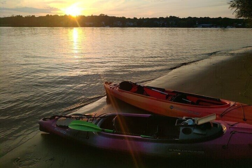 A sunset over a calm lake with two kayaks on the shore. 5