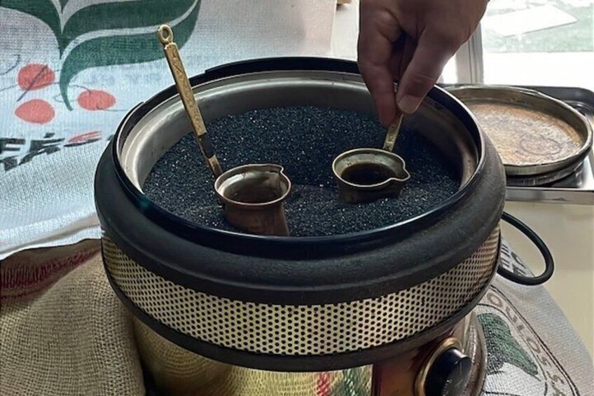 A traditional tea set with a teapot and two cups, placed on a woven mat. 5