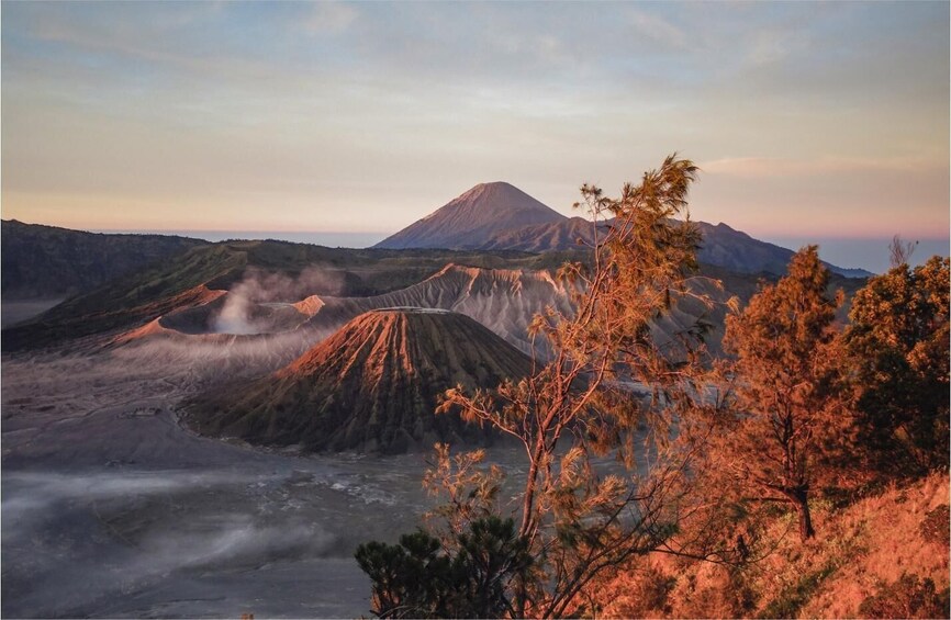 A volcanic landscape with a prominent volcano in the background, surrounded by rugged terrain and sparse vegetation. 4