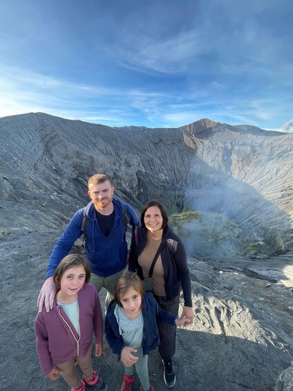 A family of four standing on a rocky outcrop with a mountainous landscape in the background. 4