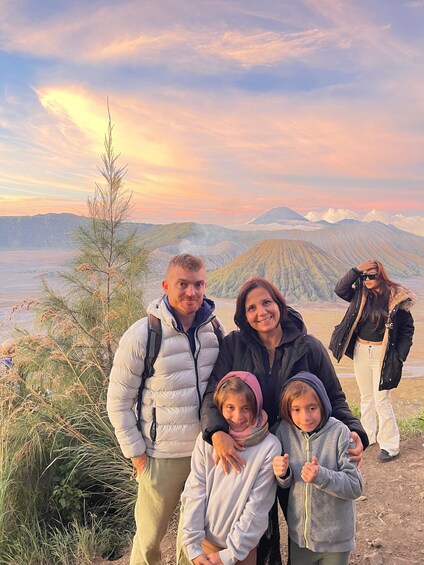 A family of four at a scenic overlook with mountains in the background. 1