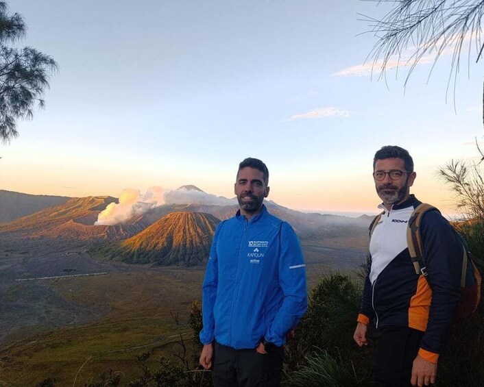 Two people standing on a hill with a mountainous landscape in the background. 3