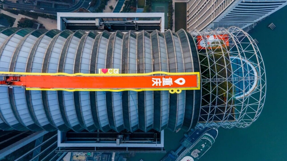 A large, modern building with a distinctive curved roof, surrounded by other high-rise structures and a body of water. 5