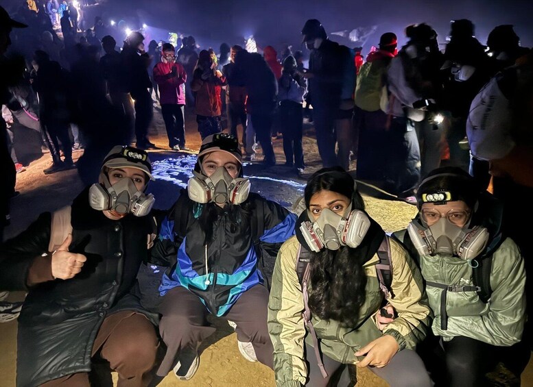 A group of people wearing gas masks and sitting on the ground. 3