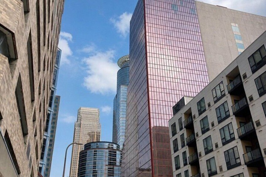 A cityscape with modern high-rise buildings, one with a distinctive pink facade and another with a curved glass design. 2