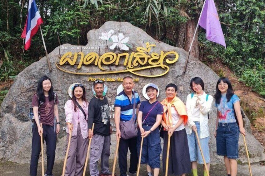 A group of people standing in front of a large rock with a sign that reads 'Khao Samet National Park' and Thai script. 2