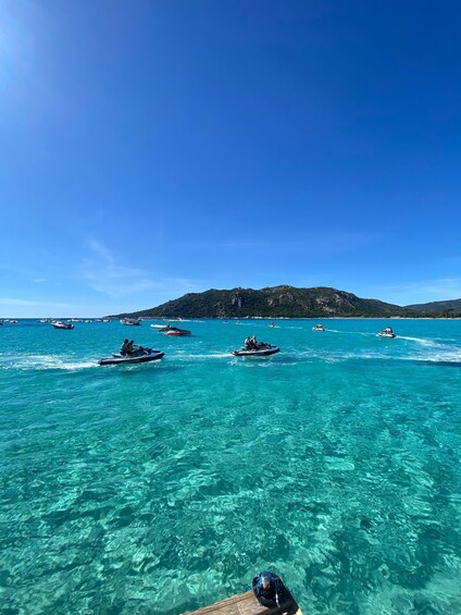 A clear blue sea with several jet skis and boats. 3
