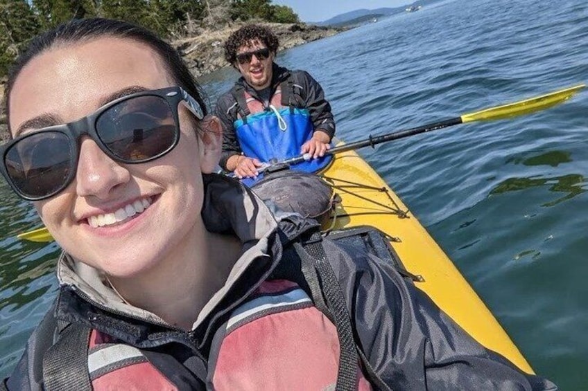 A person in a kayak on a body of water with another person paddling behind. 2