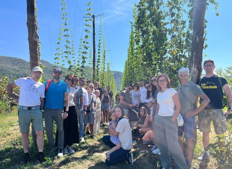 A group of people outdoors, some standing and some sitting, with trees and a clear sky in the background. 2