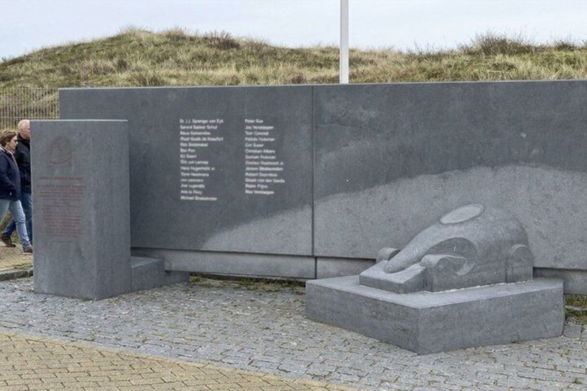 A memorial with inscriptions and a sculpture of a reclining figure. 3