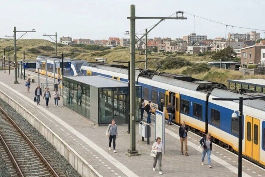 A train station platform with a train, passengers, and a modern glass shelter. 4