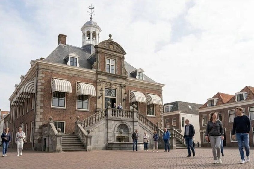 A historic building with a staircase, a bell tower, and people walking around. 5